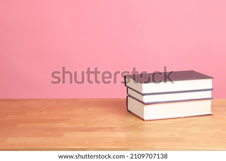 The picture of books on the working desk with pink background.