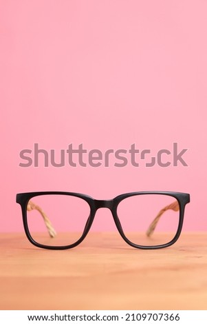 The picture of glasses on the wooden desk with color background.