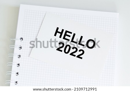 Hello 2022 text on white card on notepad, business plans