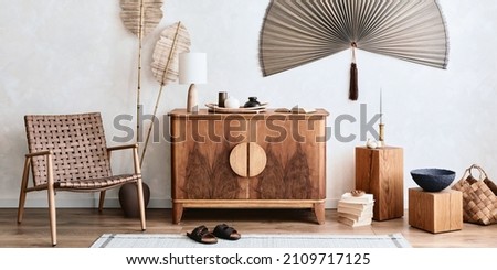 Minimalist composition of living room with wooden commode, table lamp, dried flower in vase, book, decoration and elegant personal accessories in stylish home decor. Template. Copy space.