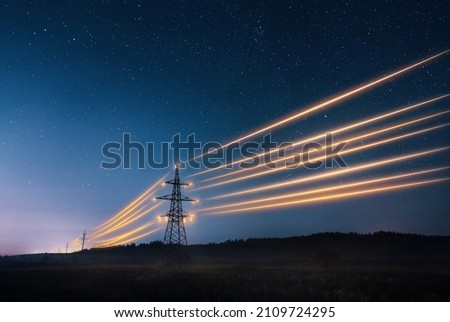Electricity transmission towers with orange glowing wires the starry night sky. Energy infrastructure concept. Royalty-Free Stock Photo #2109724295