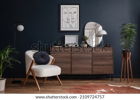 Modern living room interior composition with fluffy armchair, wooden commode, mock up poster frame, vinyl recorder and modern home accessories. Blue wall. Template. Copy space.
