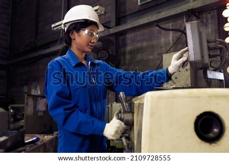 Asian factory engineer woman worker  in uniform, safety goggles checking quality control, maintenance, monitor screen checking process in factory, warehouse Workshop for factory operation.Asian woman.