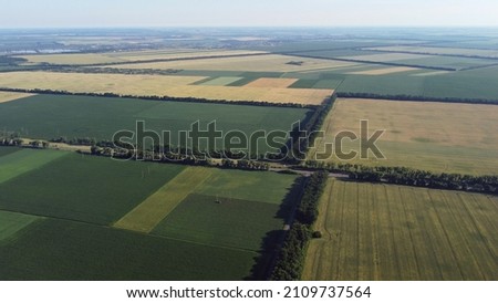 Aerial drone view flight over different agricultural fields sown with various rural agricultural cultures. Top view farmland and plantations. Landscape fields agro-industrial culture. Countryside Royalty-Free Stock Photo #2109737564