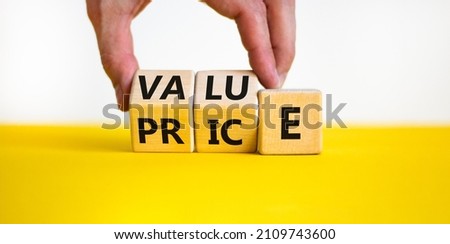 Value and price symbol. Businessman turns wooden cubes and changes the word price to value or vice versa. Beautiful yellow table, white background, copy space. Business value and price concept. Royalty-Free Stock Photo #2109743600