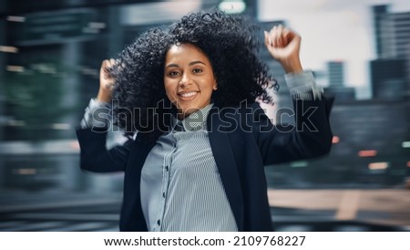 Street Shot: Cheerful and Happy Young Black Woman Dancing on the Street. African American Girl with Stylish Afro Hair Having Fun, Joyfully Expressing Herself. Blur Motion Background.