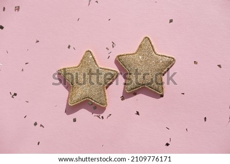 Two golden decorative stars and sparkles on a pink background. Flat lay, place for text.