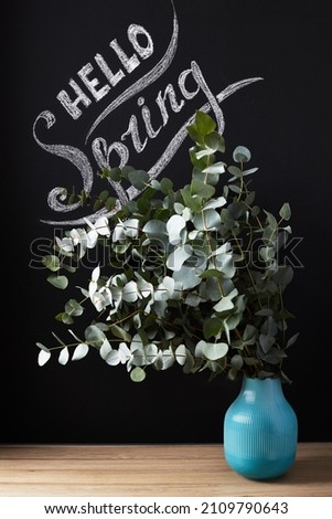 Hello spring. Seasonal photo, an inscription with flowers on a dark background of a slate wall or chalkboard. Front view.