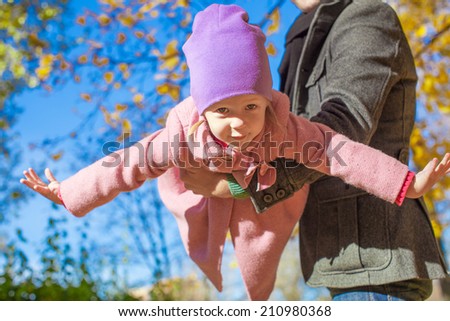 Adorable little girl with happy father outdoor in autumn