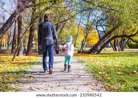 Young father and little girl walking in autumn park