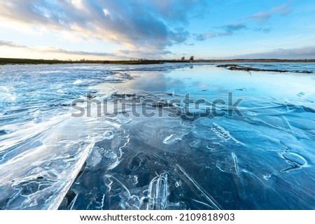 Partly frozen river in winter, sunset