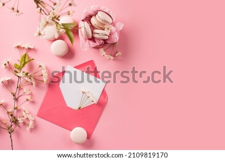 Spring Festive holiday greeting card for Valentines, Birthday, Woman, Mothers Day. Rose sweet cookies macaroons in gift box and Cherry blossoms on pink background. Top view, copy space, flat lay.
