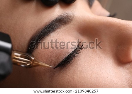Young woman undergoing procedure of permanent eye makeup in tattoo salon, closeup Royalty-Free Stock Photo #2109840257
