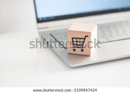 Wooden cube with shopping chart on laptop keyboard. Online Shopping concept	