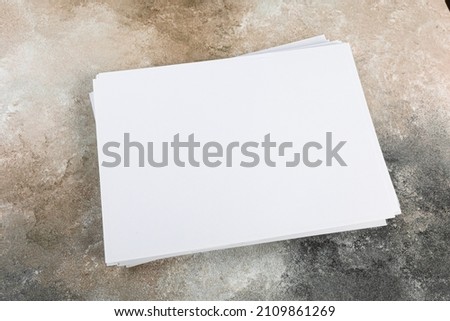 several sheets of paper in a pile of a4 a5 business card on a grunge table.