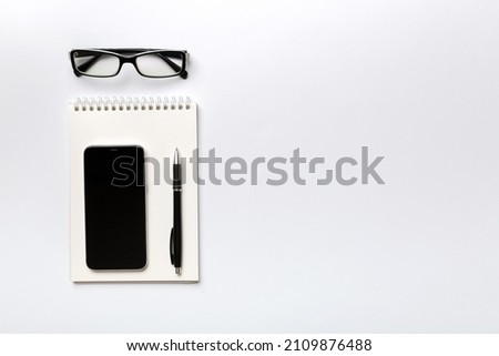 Smartphone with a notebook on a light Color background. top view.