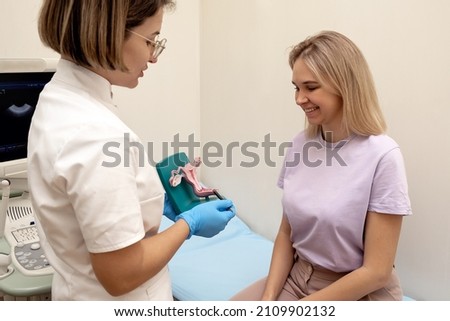 Gynecologist talks to a patient with a model of the female reproductive system in her hands.Women's health, pregnancy planning,pathology of internal organs,medical concept. Royalty-Free Stock Photo #2109902132