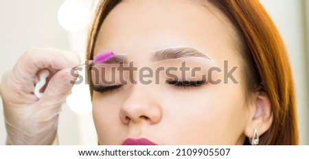 The makeup artist combs his eyebrows with a brush. Marking with a white pencil. Permanent makeup. Staining with henna paint.