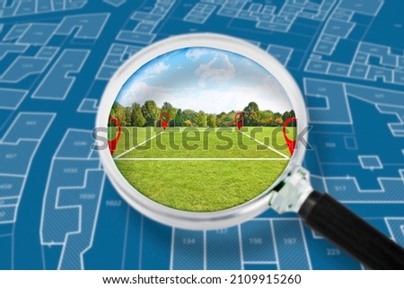Land management with an imaginary cadastral map of territory with a vacant land available for sale or building construction - Concept seen through a magnifying glass  Royalty-Free Stock Photo #2109915260
