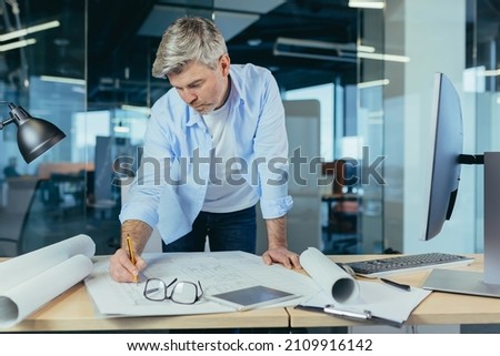 An experienced architect working on a drawing, a man in a modern office at the computer, a designer draws a modern project