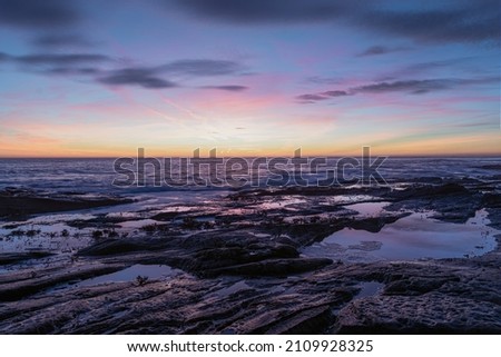 Beautiful sunrise at the coast early morning with waves crashing onto the rocks 