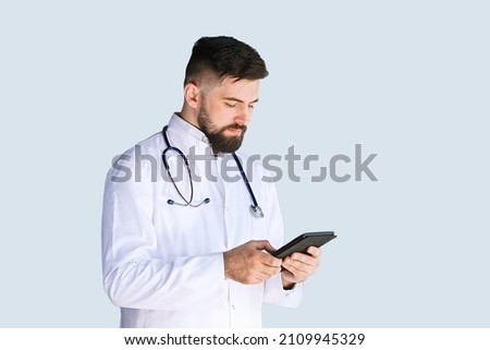 Healthcare, medicine concept: Handsome Doctor thinking about diagnosis on tablet computer isolated over grey color background Royalty-Free Stock Photo #2109945329