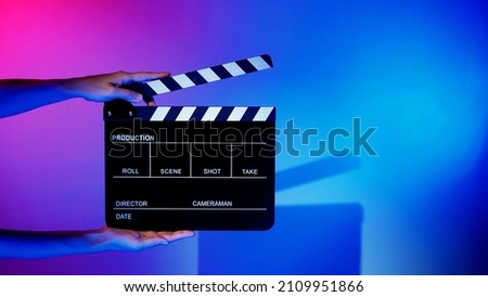 Blurry images of movie slate or clapper board. Hand holds empty film making clapperboard on color background in studio for film movie shooting or recording. Film slate for Youtuber video production. Royalty-Free Stock Photo #2109951866