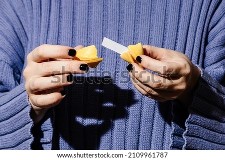 Women's hands hold a fortune cookie.  Royalty-Free Stock Photo #2109961787