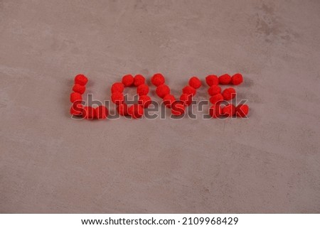 the word love and a heart made of fluffy balls on a red background .the concept of Valentine's day and all lovers