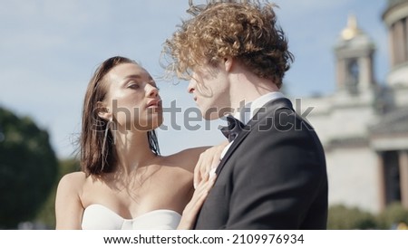 Beautiful couple of newlyweds look at each other. Action. Beautiful couple of newlyweds passionately look at each other. Newlyweds pose on windy sunny day in summer city Royalty-Free Stock Photo #2109976934