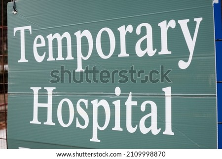 "Temporary Hospital" sign hung on fence at entrance.