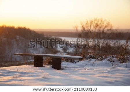 Bench on a hill above the river during the winter sunset.