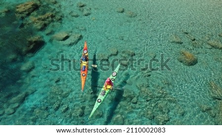 Aerial drone photo of women team of sport kayak paddling in iconic beach and small cove of Tsigrado, Milos island, Cyclades, Greece