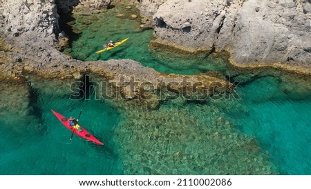 Aerial drone photo of women team of sport kayak paddling in iconic beach and small cove of Tsigrado, Milos island, Cyclades, Greece