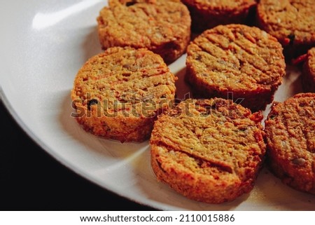 Vegetarian, round patties in a white pan that are not yet fried.