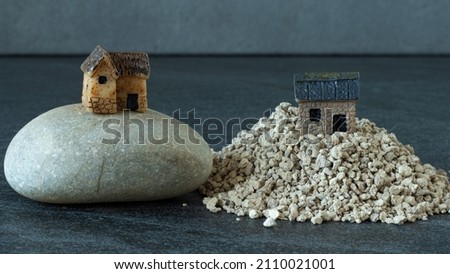 Two miniature houses, one built on a rock, and the other built on a sand. Jesus Christ parable of wise and foolish Christian. The biblical concept of faith and obedience to God. A close-up. Royalty-Free Stock Photo #2110021001