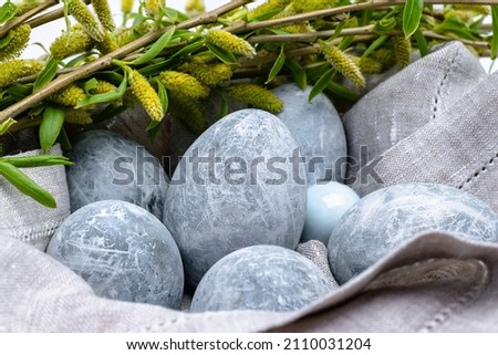 Easter background. Close-up of marble-colored Easter eggs in a linen napkin with willow sprigs. Horizontal photo.