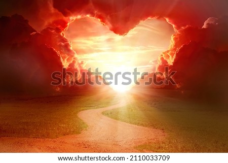  Red heart shaped sky at sunset. Beautiful landscape with road and clouds.Love background with copy space. Road to love  Royalty-Free Stock Photo #2110033709