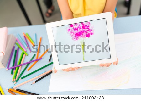 Close-up schoolgirl holding a digital tablet with a picture of firework