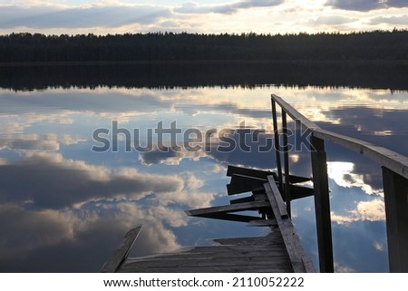 a flooded pier in the water with a reflection of the sky