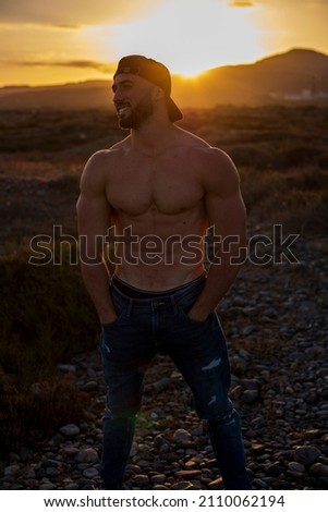 shirtless muscular caucasian man posing with sunset. street photography
