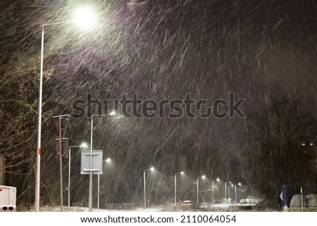 Strong snowfall at night in the light of lanterns. Royalty-Free Stock Photo #2110064054