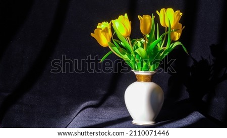A beautiful bouquet of yellow spring tulips in a stylish porcelain white vase on a black background rotates around its axis. Spring Women's Day. Soft fox toy. Floristics. Dutch flower.