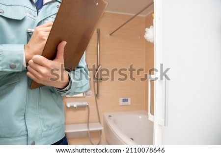 A man wearing work clothes and inspecting the bathroom Royalty-Free Stock Photo #2110078646