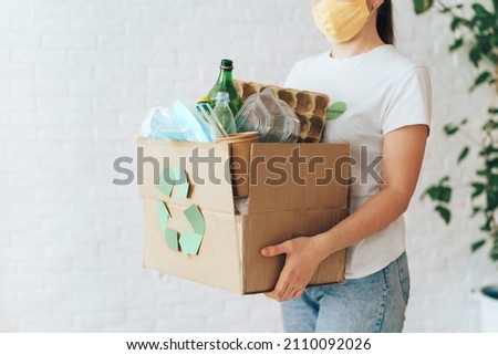 Girl carries box of garbage for recycling.