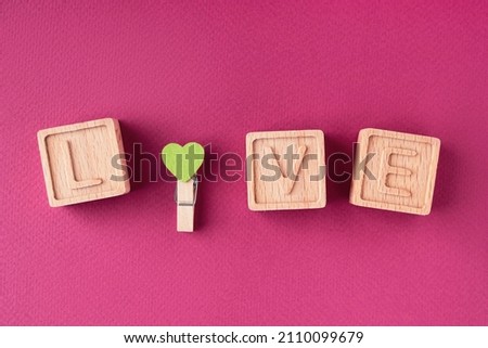 The word love is made up of wooden cubes on a bright pink background flat lay, top view. The theme of love and romance. The concept of a greeting card for Valentine's Day, Mother's Day, Women's Day