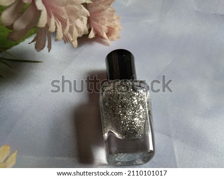 Nail polish bottle with sparkle color, flower and white background