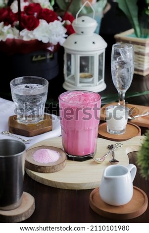 Ice red velvet latte after mixed with powder on table and coaster, spoon and glass accessories for match picture.