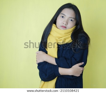 Beautiful young girl wear yellow scarf and blue sweater on yellow background.