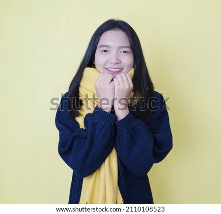 Beautiful young girl wear yellow scarf and blue sweater on yellow background.